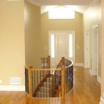 Rich, golden, solid hardwood flooring by Meistercraft complements the rounded stair and wrought iron railing in this modern home