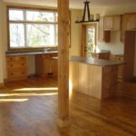 Rich hardwood flooring by Meistercraft Wood Flooing complements the kitchen cabinets in this rustic cottage