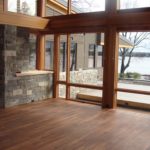 Custom hardwood flooring by Meistercraft complements the stone interior wall and glass exterior wall overlooking the grounds and lake beyond