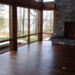 Custom hardwood flooring by Meistercraft complements the massive stone fireplace and glass wall overlooking grounds and lake in this vaulted greatroom