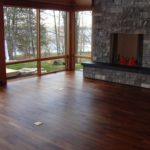 Custom hardwood flooring by Meistercraft complements the massive stone fireplace and glass wall in this vaulted greatroom