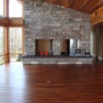Custom hardwood flooring by Meistercraft complements the massive stone fireplace in this vaulted greatroom