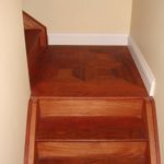 Stairway landing with custom inlay & hardwood stairs by Meistercraft Wood Flooring