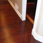 Dark hardwood flooring in hallway meets intricate inlay in office hardwood floor; custom flooring by Meistercraft Wood Flooring