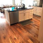 Lustrous hardwood complements the off-white island and cupboards in this open-concept kitchen; custom hardwood floor by Meistercraft Wood Flooring