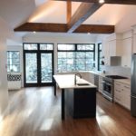 Dark brown hardwood flooring anchors this bright open concept kitchen with vaulted ceiling; custom flooring by Meistercraft