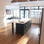 Rich custom hardwood flooring anchors this bright open concept kitchen with vaulted ceiling; custom flooring by Meistercraft