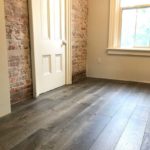 Custom hardwood flooring complements the beauty of a red brick wall; custom hardwood by Meistercraft Wood Flooring