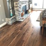 Rich, dark, solid hardwood flooring complements the stone fireplace and hearth in this elegant livingroom; custom wood flooring by Meistercraft