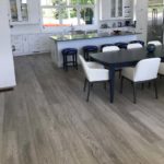 Gray hardwood flooring complements the white cupboards in this modern open concept kitchen; custom hardwood floor by Meistercraft Wood Flooring