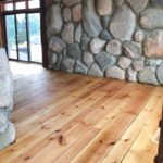 Solid hardwood flooring complements this beautiful and massive stone interior wall; hardwood flooring by Meistercraft