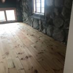 Solid hardwood flooring complements this rustic stone interior wall; hardwood flooring by Meistercraft