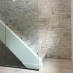 Light coloured hardwood stairs complement the glass & limestone walls; custom hardwood flooring by Meistercraft